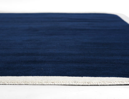 Rectangular navy runner rug with a light cream border along the edge.
