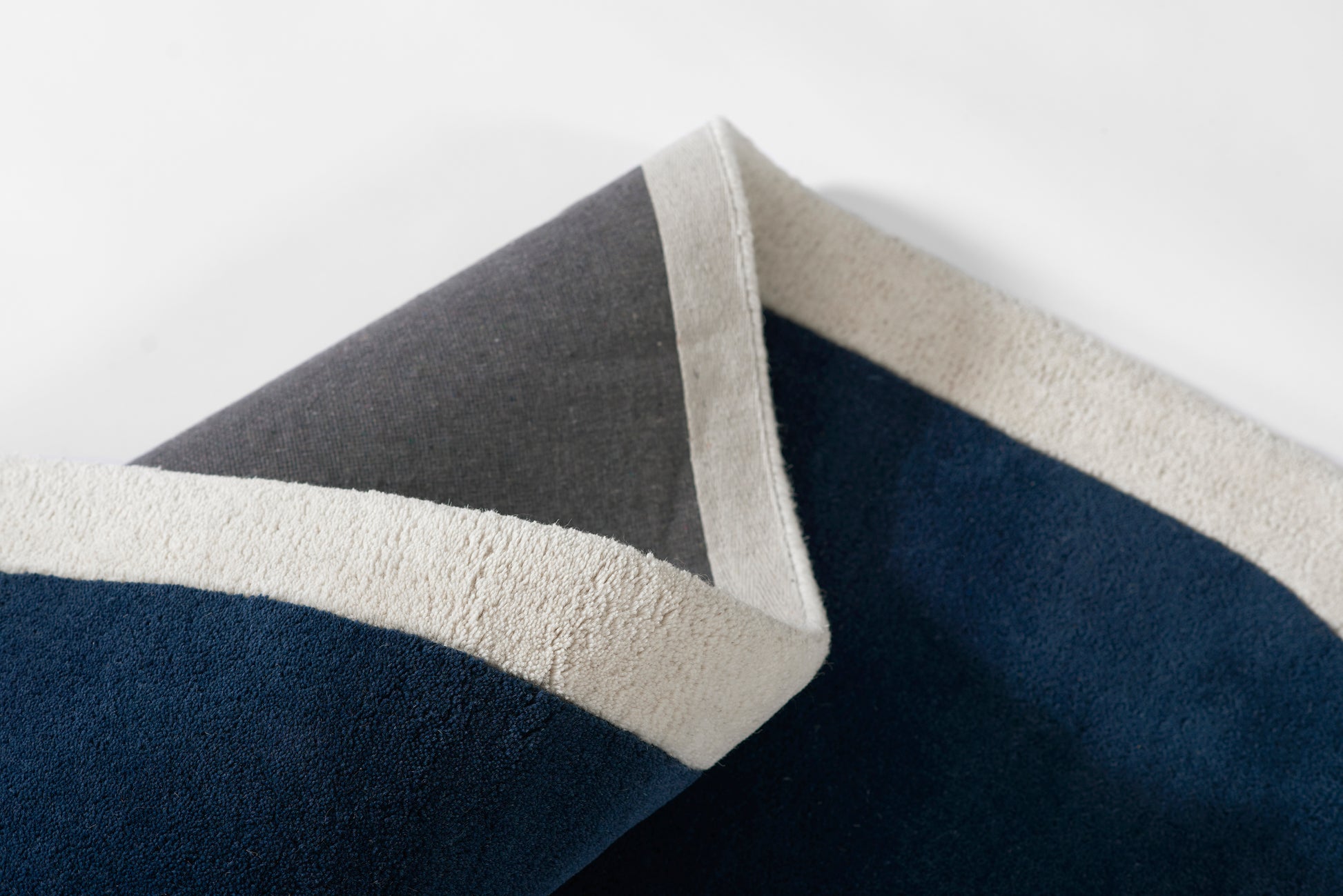 Dark navy towel with ivory cream border and light gray edge; plush terry, color-block style, folded.