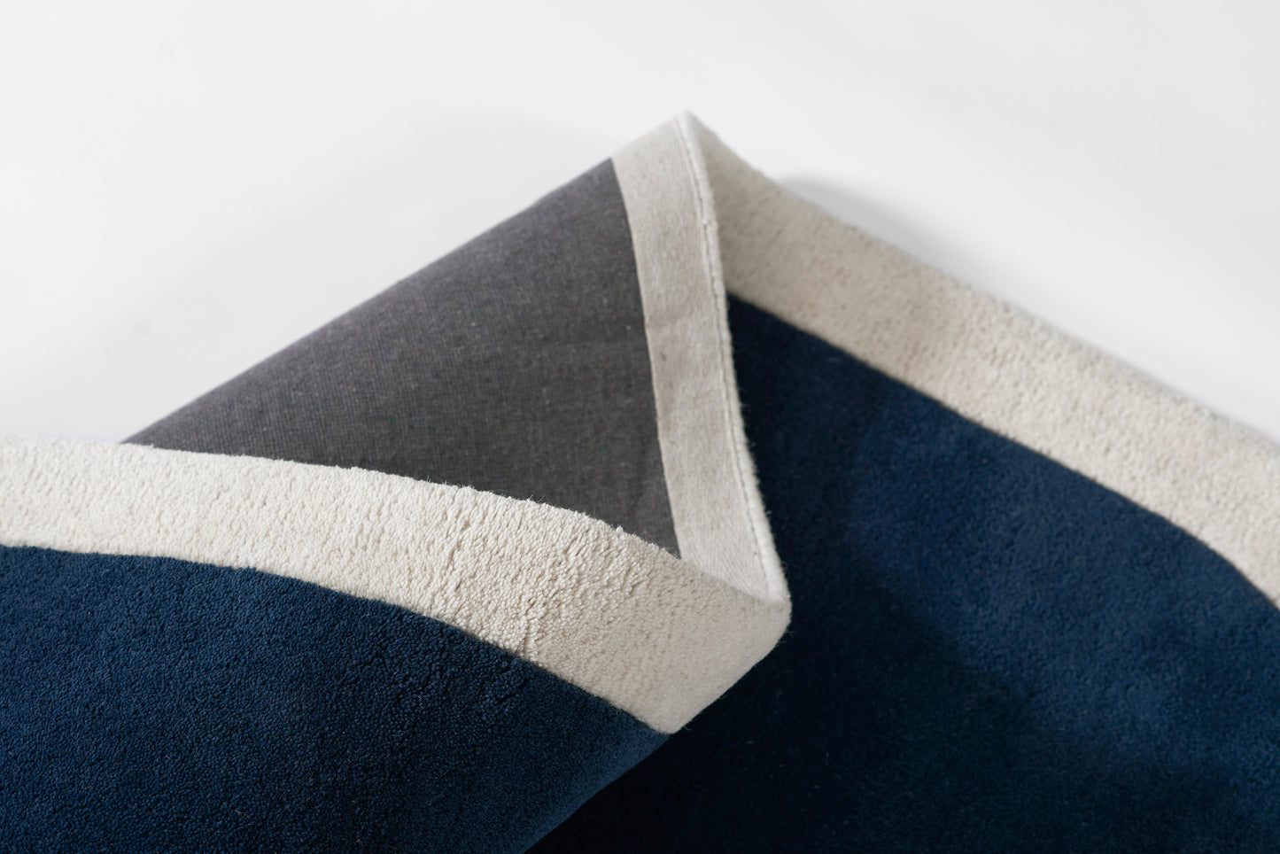 Navy blue and gray color-block rug with cream border, soft texture, folded for display.