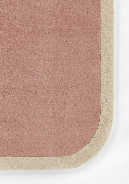 Dusty pink rug with pale beige border and rounded corner; soft plush texture for modern living spaces.