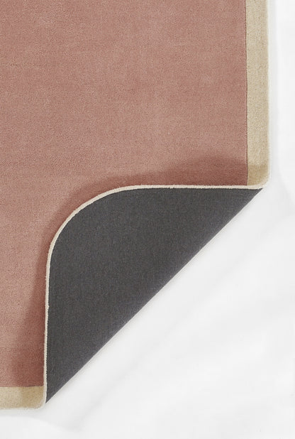 Pink rug with beige trim, folded corner reveals dark gray underside; modern rectangular layered rug.