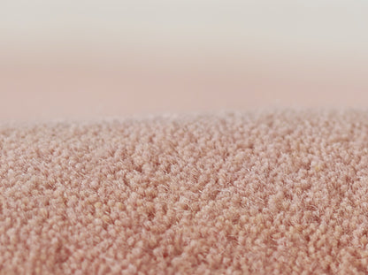 Close-up of soft pink plush carpet fibers with dense, fuzzy pile.