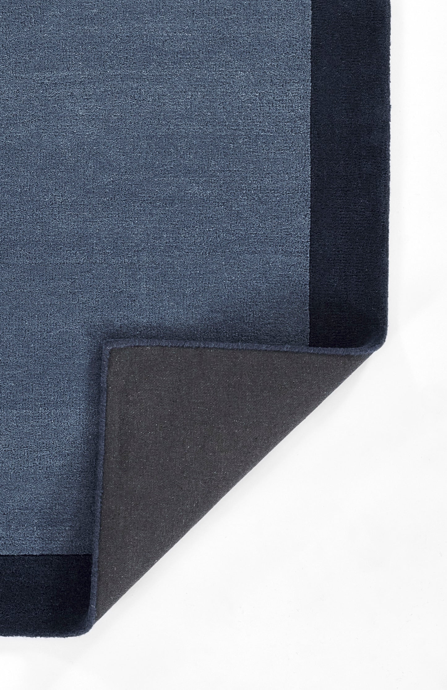 Soft textured blue rug with a lighter blue surface and dark navy border; folded corner reveals gray backing.