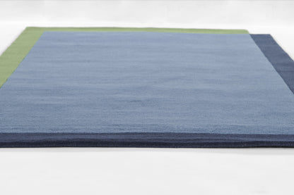 Rectangular rug with light blue central field, green left border and navy right border; modern flat-weave.
