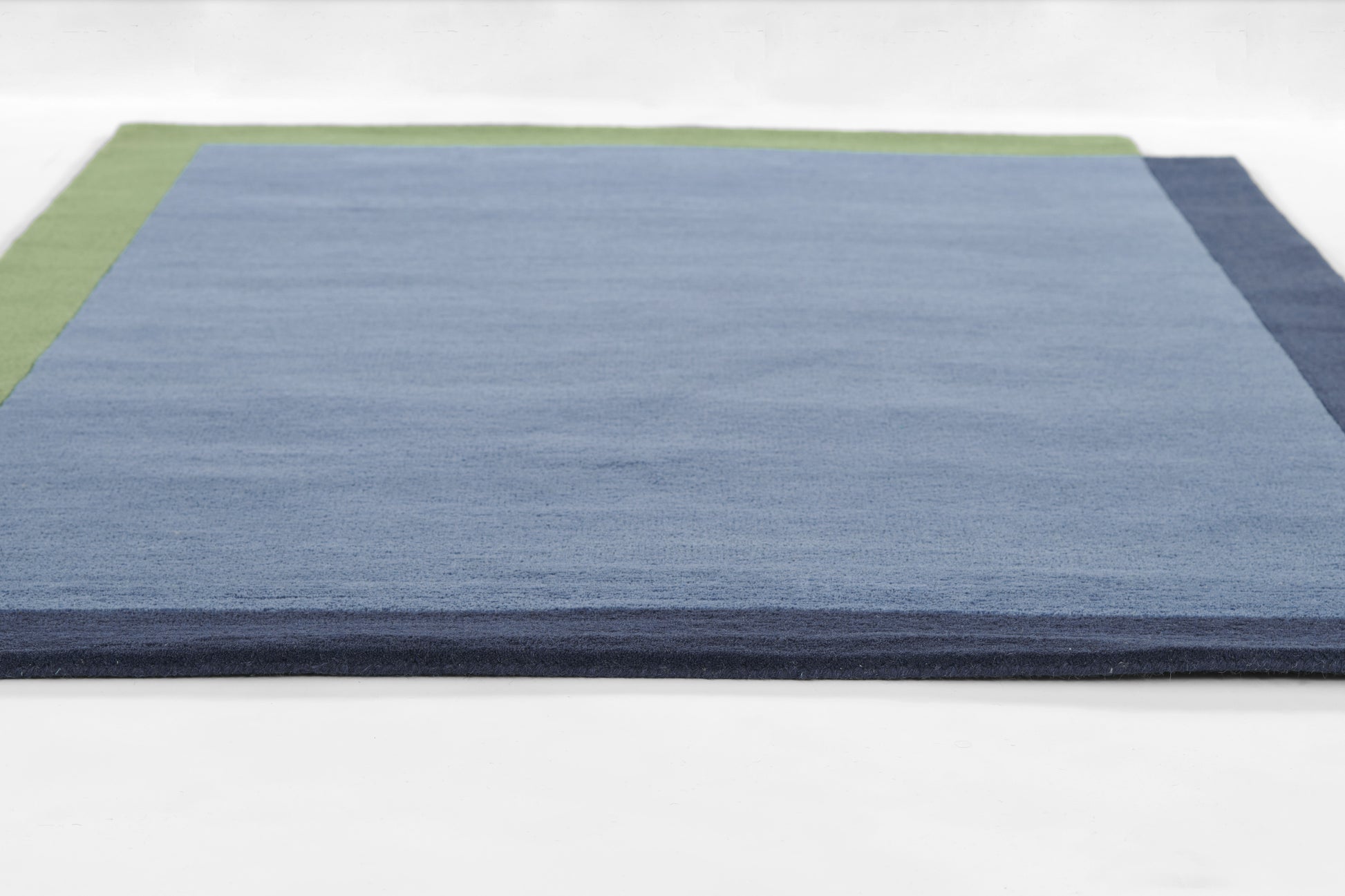 Color-block rug: pale blue central panel with lime green border on left and navy border on right.