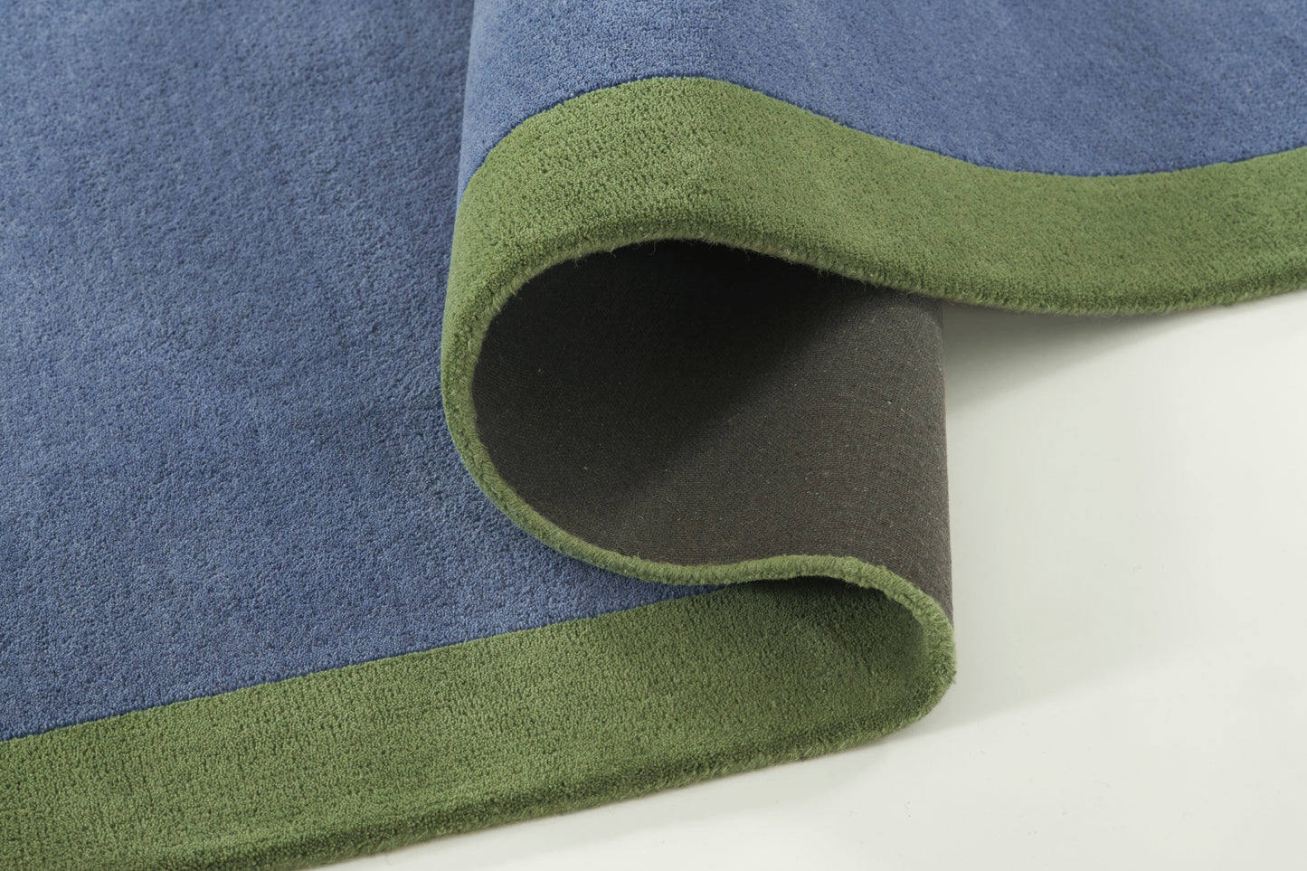 Soft plush fleece blanket in blue with olive-green reverse and green edge, partially rolled to show two-tone sides.