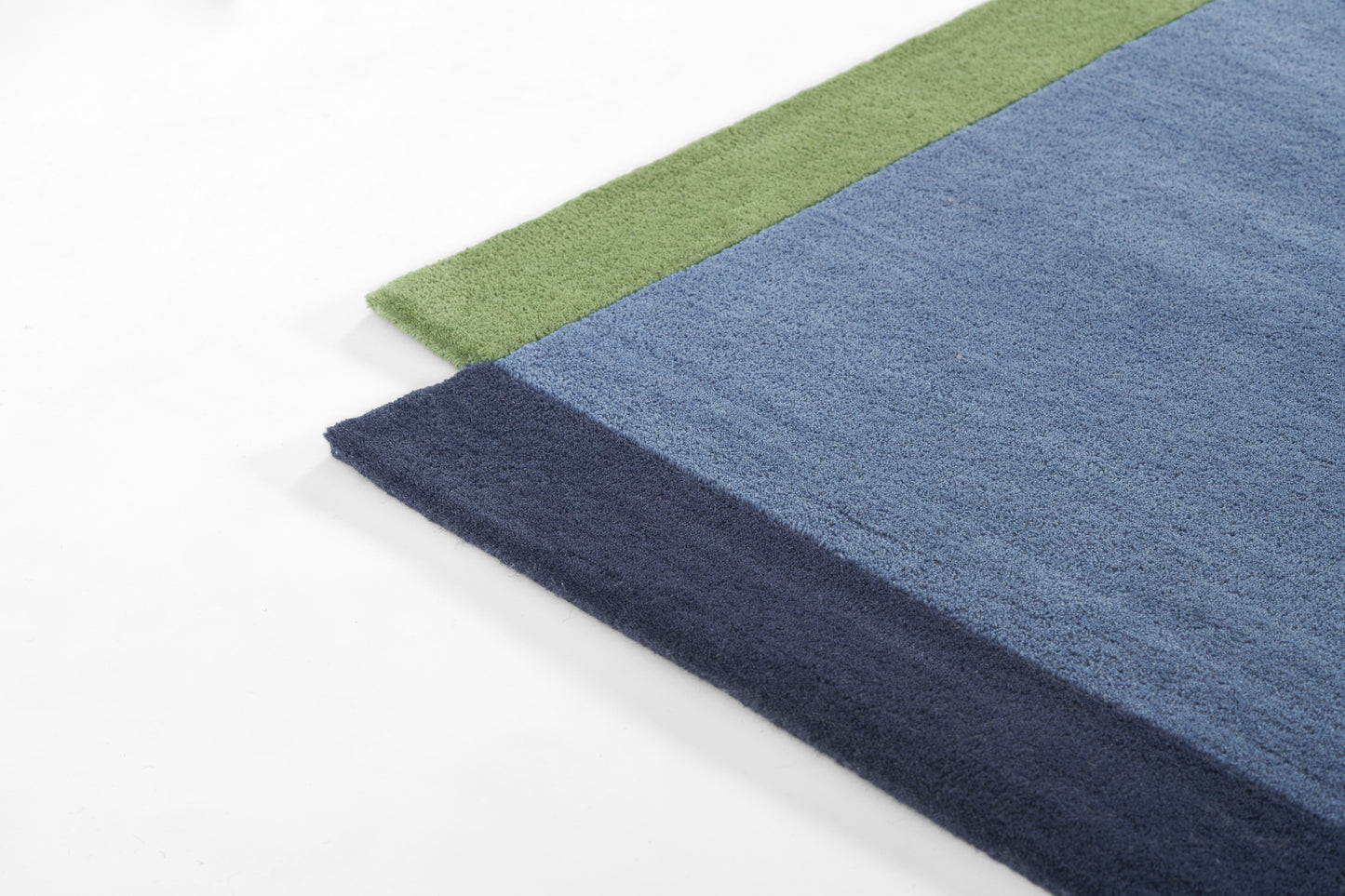 Rectangular plush rug with color-block design: green edge, light blue field, and dark navy border, soft shaggy texture.
