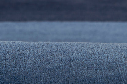 Blue textured plush carpet close-up with dense looped pile, soft and thick for living room flooring.