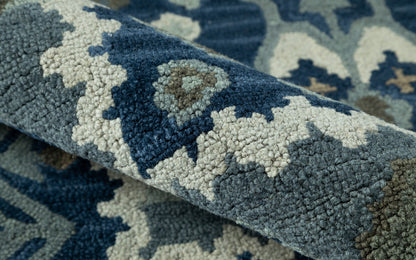 Close-up of a rolled blue and beige patterned rug with navy geometric motifs and plush textured pile.