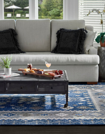 Industrial black metal coffee table on casters with mesh drawers, on a blue patterned rug in a modern living room.