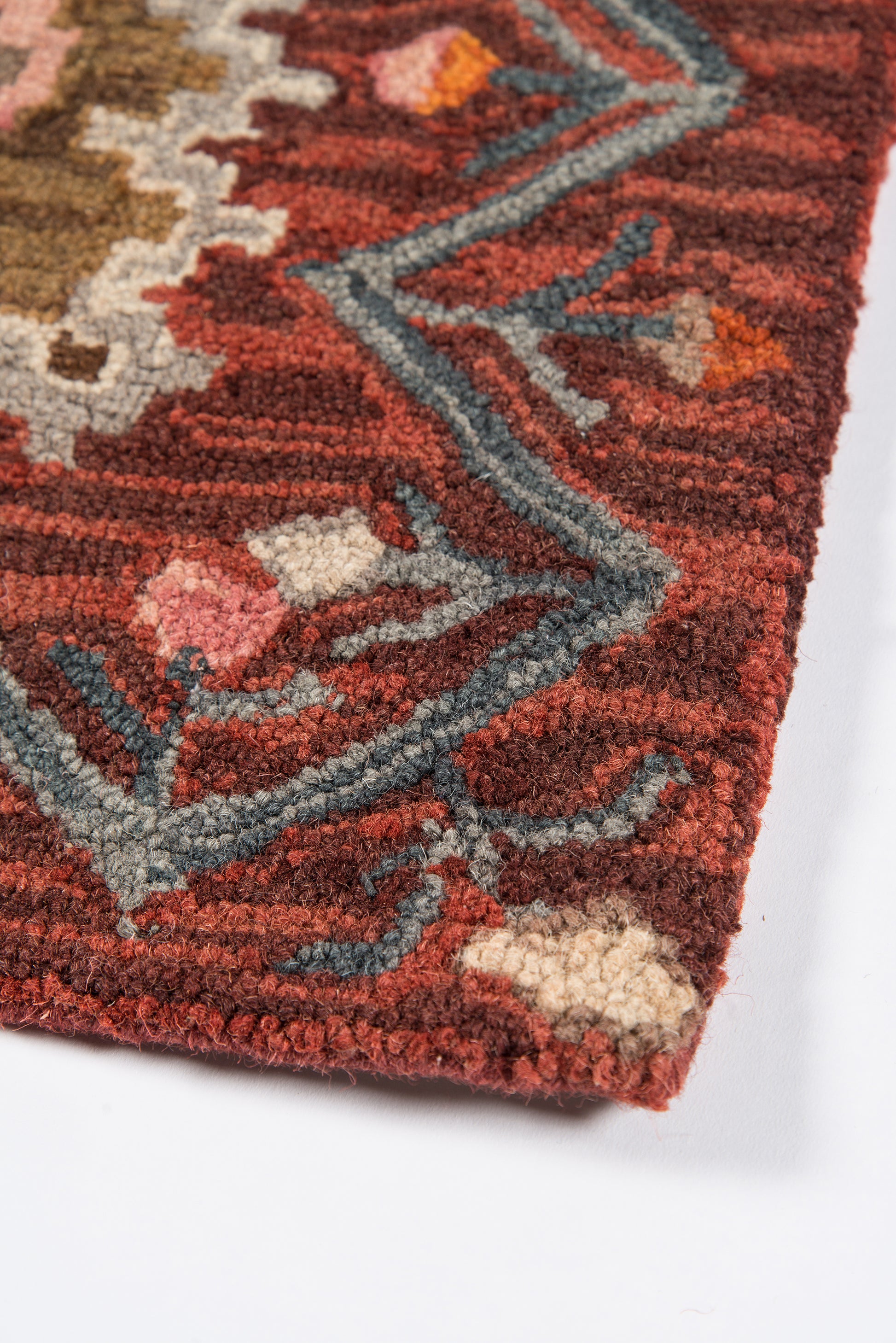 Red oriental rug corner with blue-gray border scrolls and beige floral accents; plush tufted pile.
