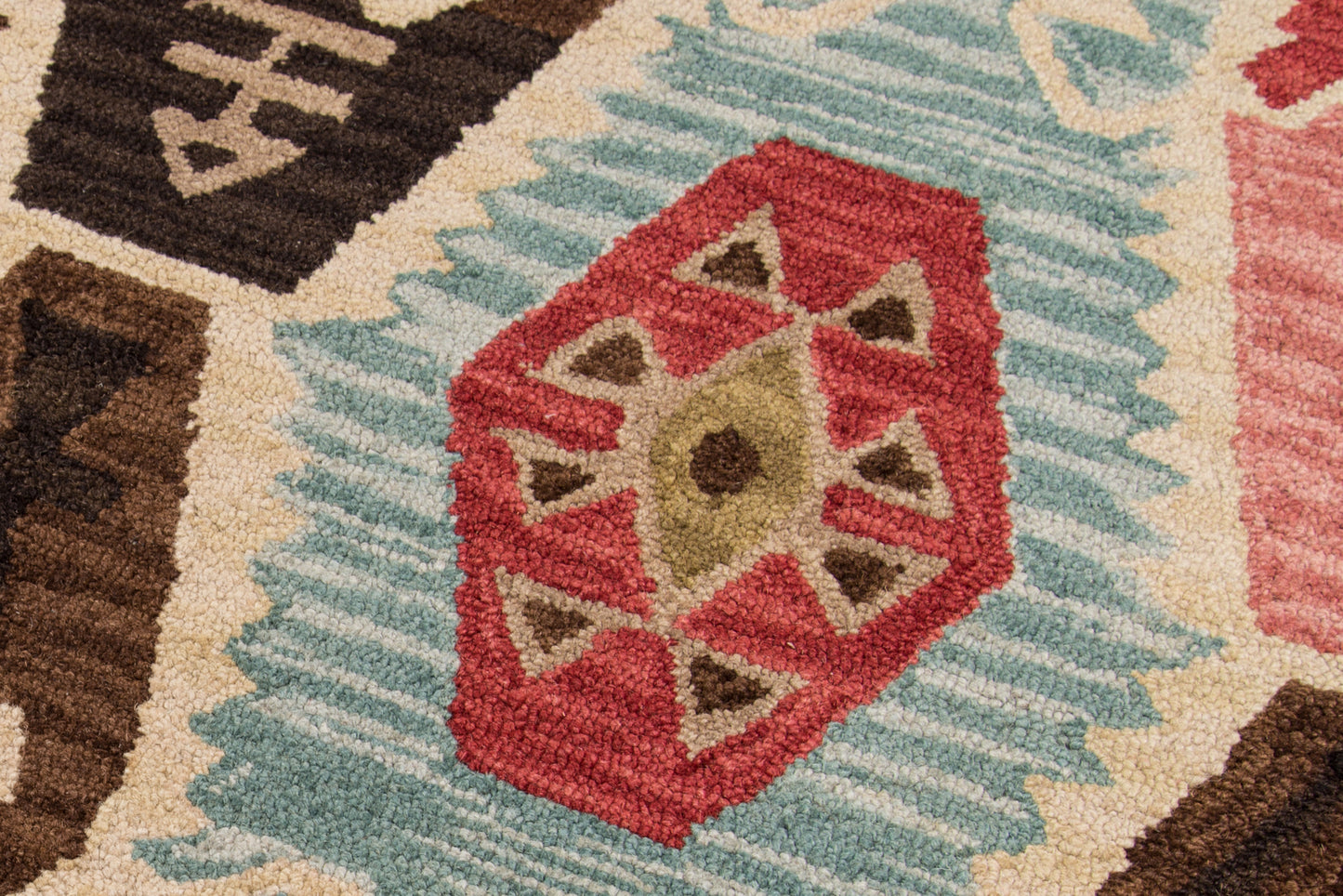 Colorful geometric rug featuring red hexagonal motif with beige triangles, teal border, brown accents, tribal style.
