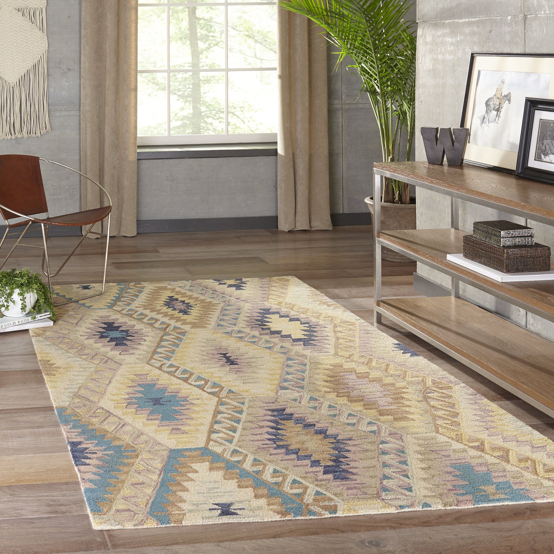 Beige geometric area rug with blue, yellow and purple accents on a wood floor in a modern living room.
