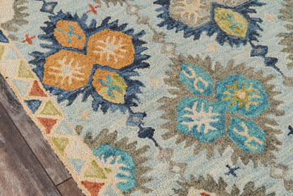 Colorful oriental rug with teal, orange and blue floral medallions on a pale blue field; geometric border on a wood floor.