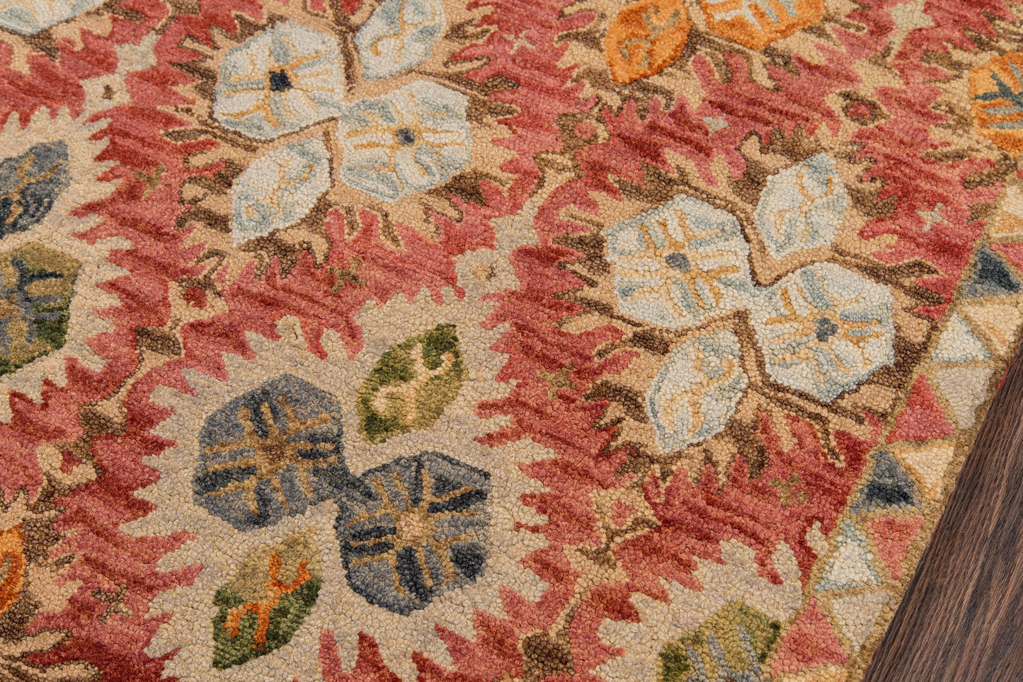 Red oriental-style rug with cream, blue, yellow and green floral motifs; textured woven pile on wood floor.