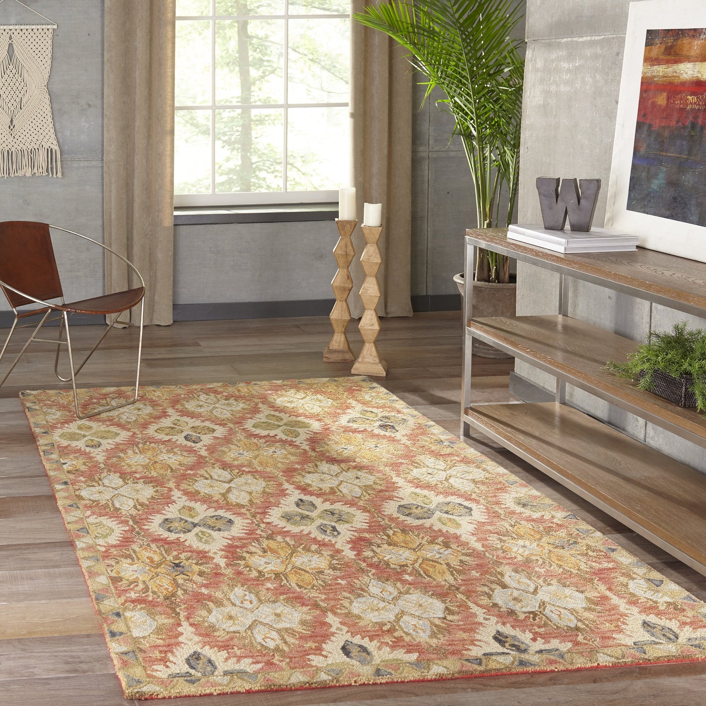 Floral medallion area rug in cream and red tones on wood floor, inside a modern boho living room with plant and console.