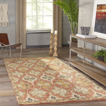 Floral medallion area rug in cream and red tones on wood floor, inside a modern boho living room with plant and console.