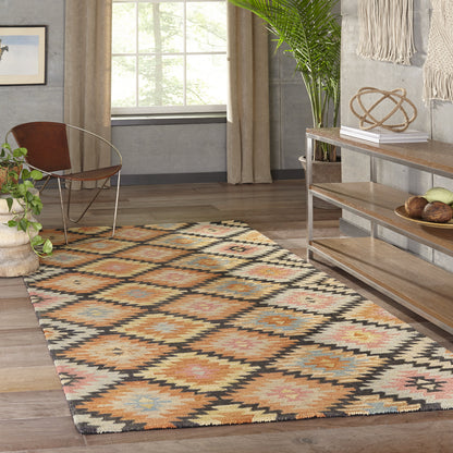 Kilim-style diamond-pattern area rug in orange, cream, tan, blue and black on wood floor in living room.
