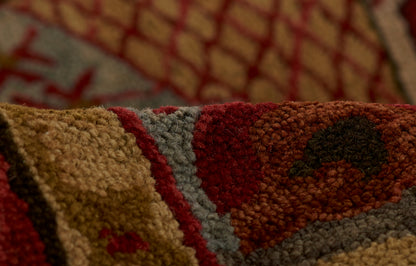 Close-up of a thick tufted rug with red, tan, gray and brown geometric pattern.
