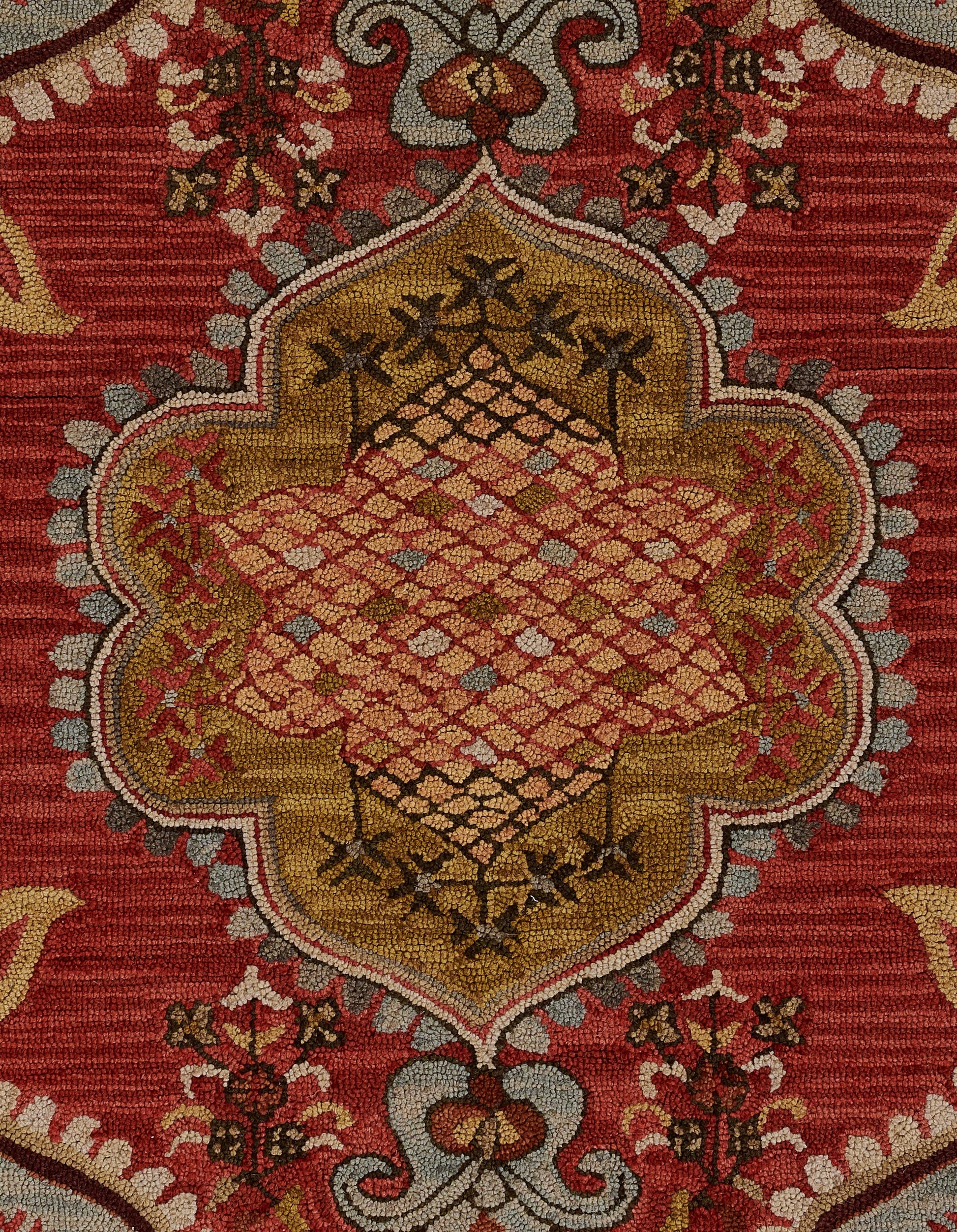 Red oriental rug with a gold central medallion, lattice diamond field and floral border patterns.