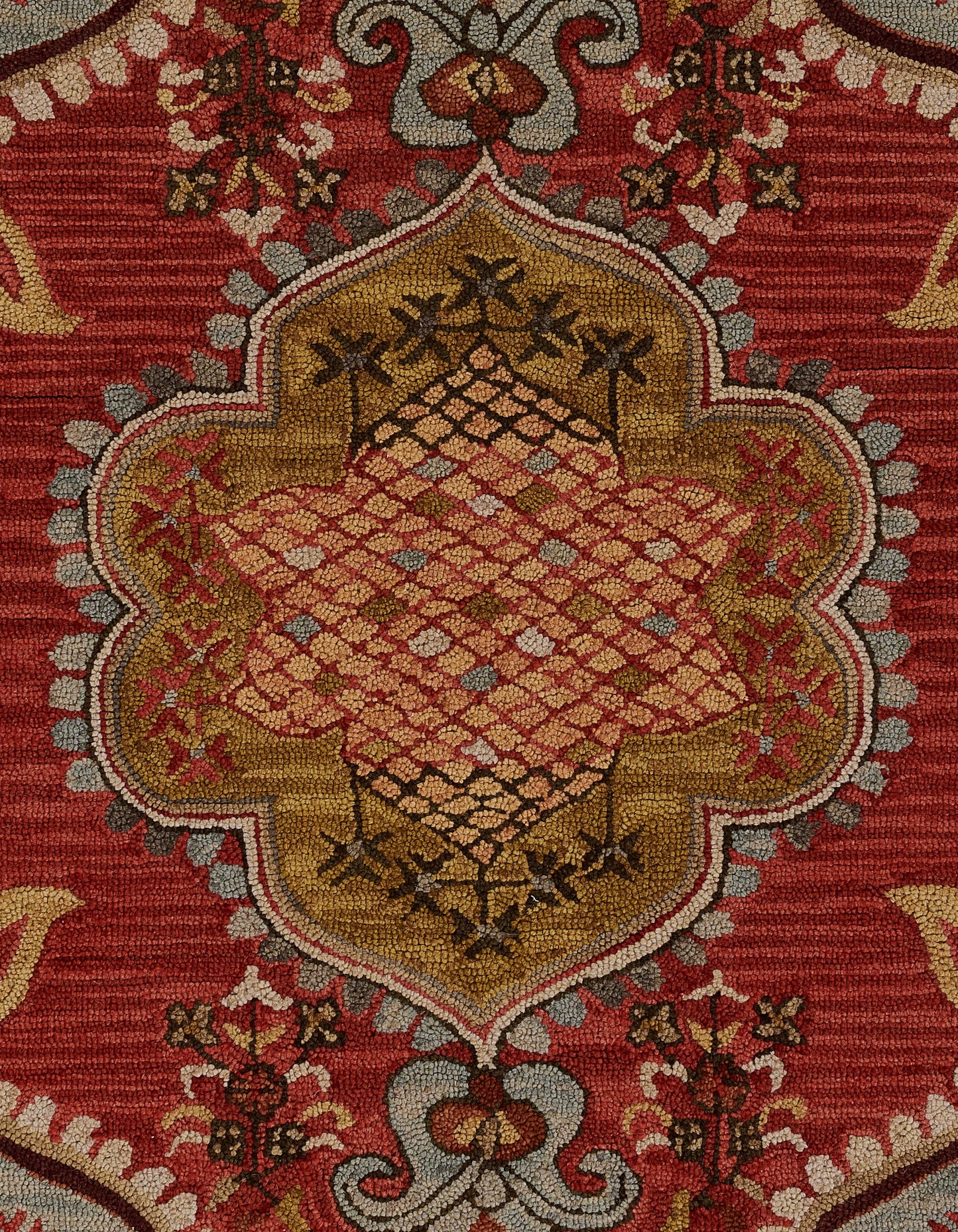 Red Persian-style rug featuring a gold central medallion, pink lattice diamonds, and a detailed floral border.