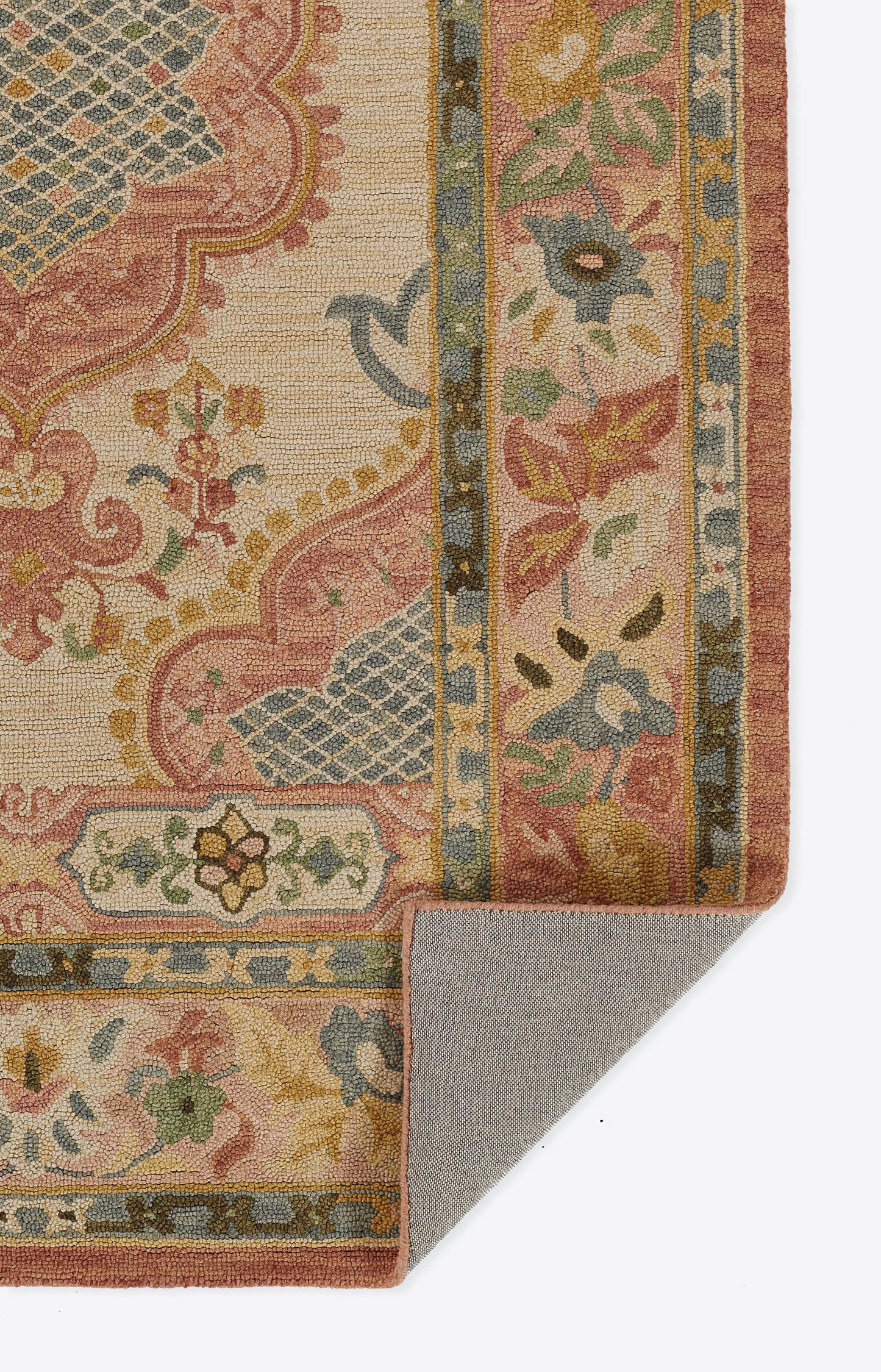 Oriental floral rug in pink, ivory, blue and green with decorative border; woven texture, folded corner reveals backing.