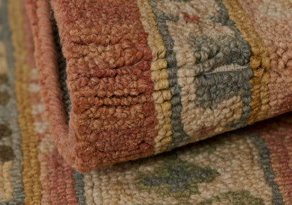 Close-up of a thick tufted wool rug in earthy rust, tan, olive and blue geometric pattern, rolled edge.
