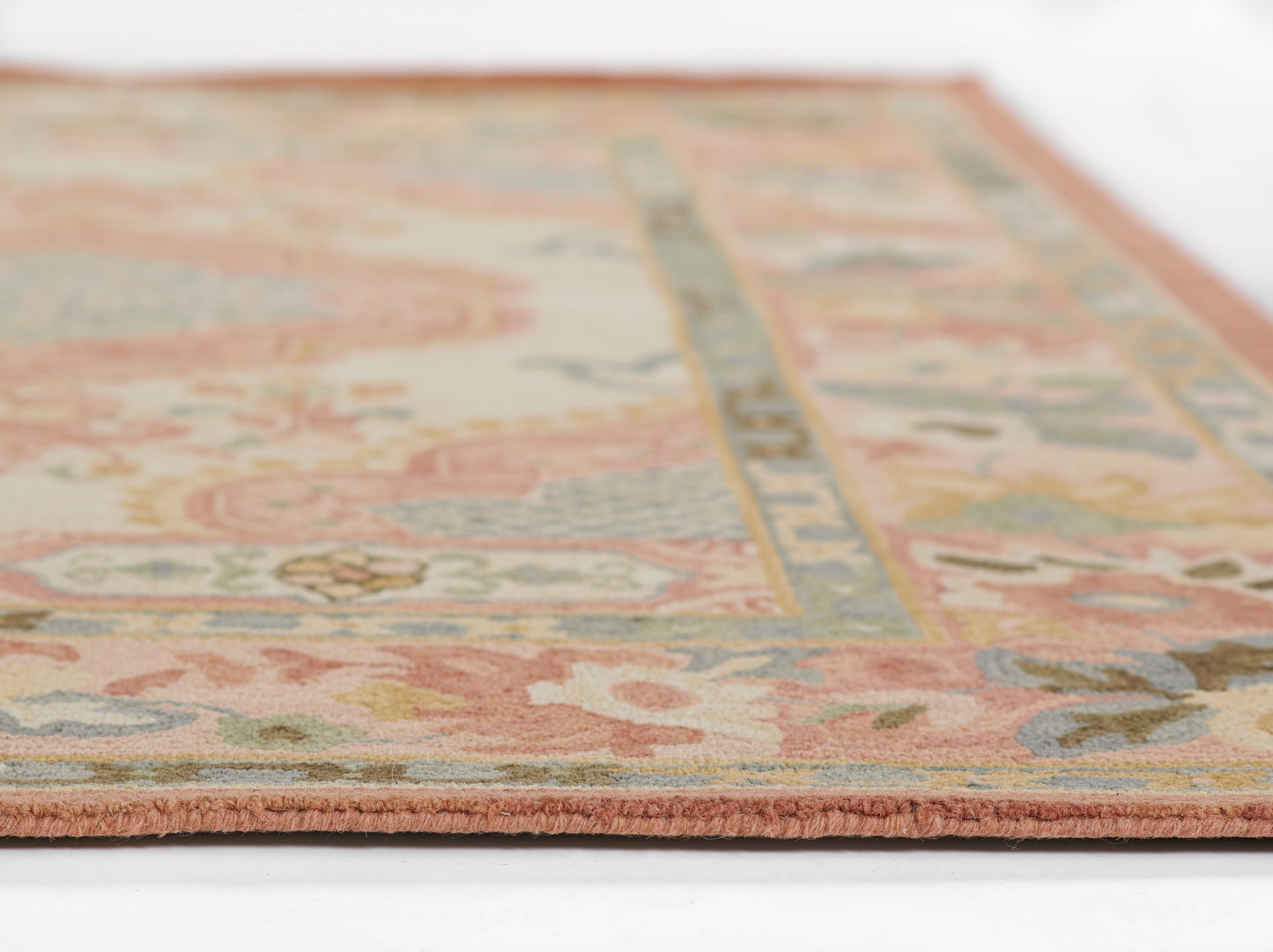 Pastel floral oriental rug with pink border, cream field and blue, green, coral accents; fringe at edge.