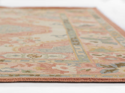 Pastel floral oriental rug with pink border, cream field and blue, green, coral accents; fringe at edge.