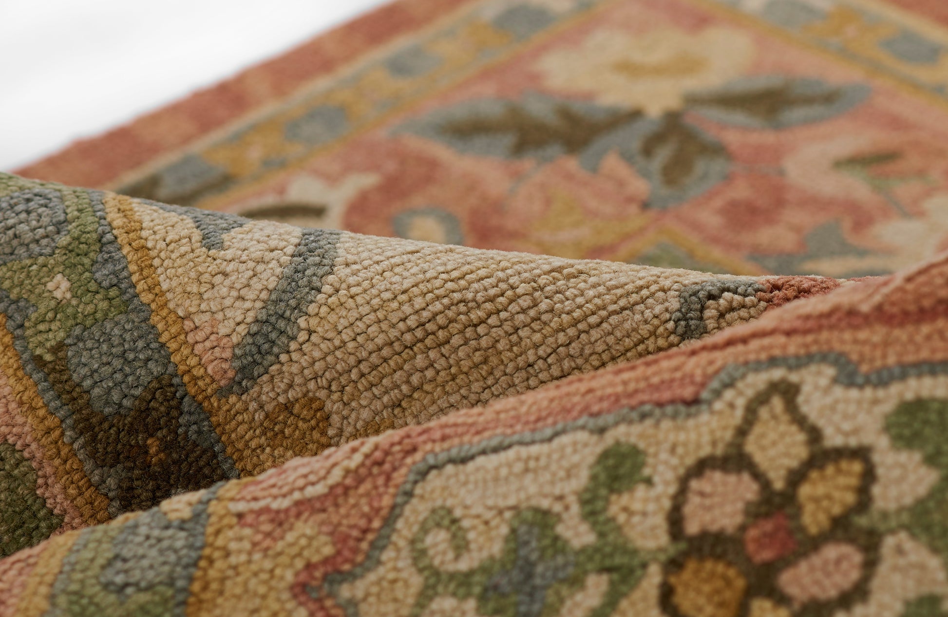 Close-up of a thick-pile, textured oriental rug with floral pattern in rust, olive, beige and blue tones.