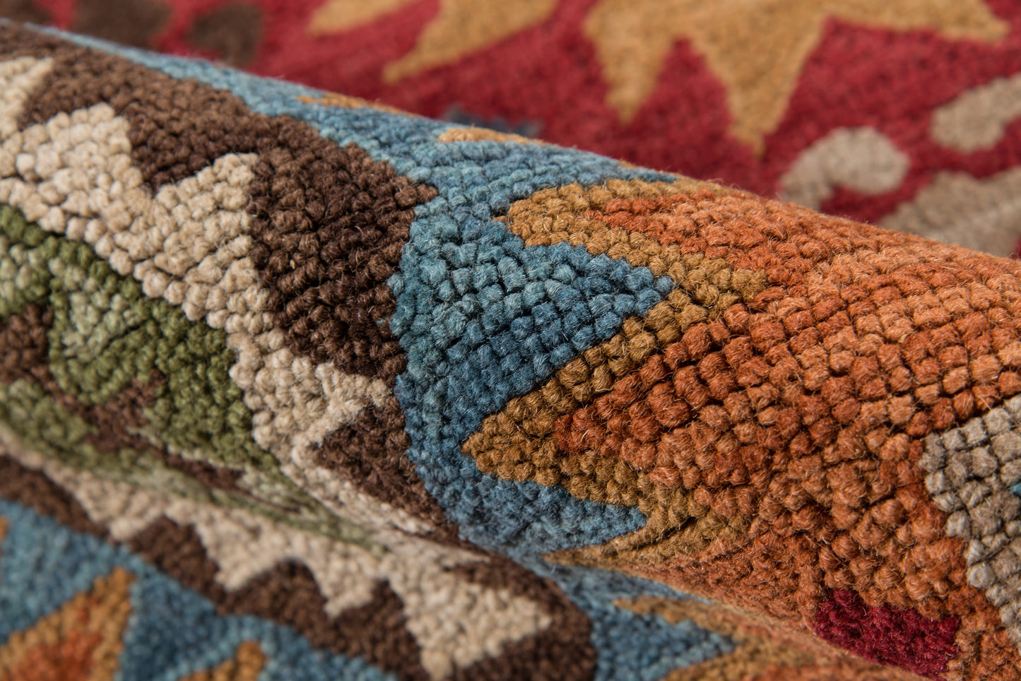 Close-up of a multicolor geometric rug with tight tufted pile; blues, teal, orange, rust, brown, cream and olive tones.