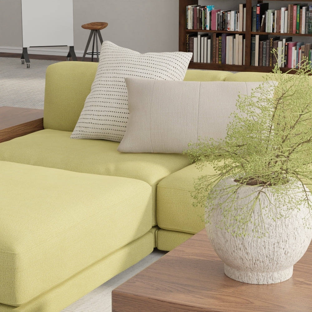 Modern living room with lime-yellow sectional, neutral and dotted cushions, wooden coffee table, potted plant, and a bookcase.
