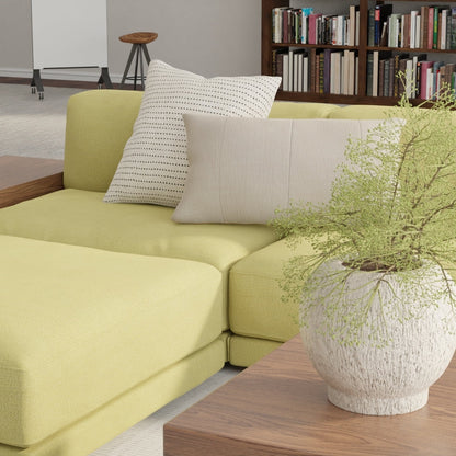 Modern living room with lime-yellow sectional, neutral and dotted cushions, wooden coffee table, potted plant, and a bookcase.