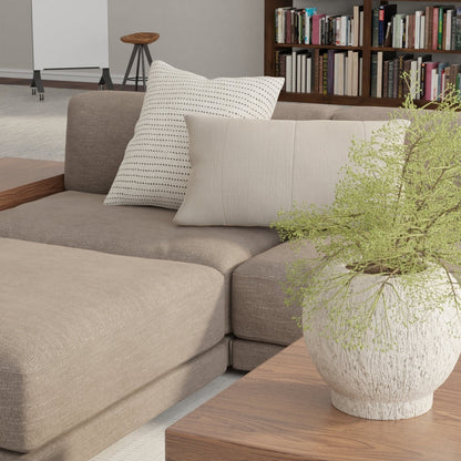 Modular sofa upholstered in mushroom solid fabric with cream cushions, wooden coffee table, and a potted fern in a living room.