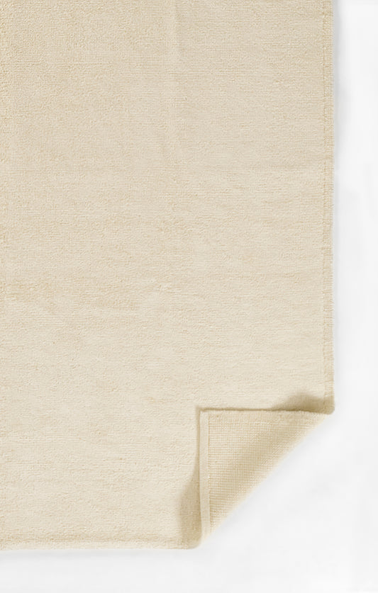 Beige plush terry cloth towel with folded corner; soft bathroom linen.