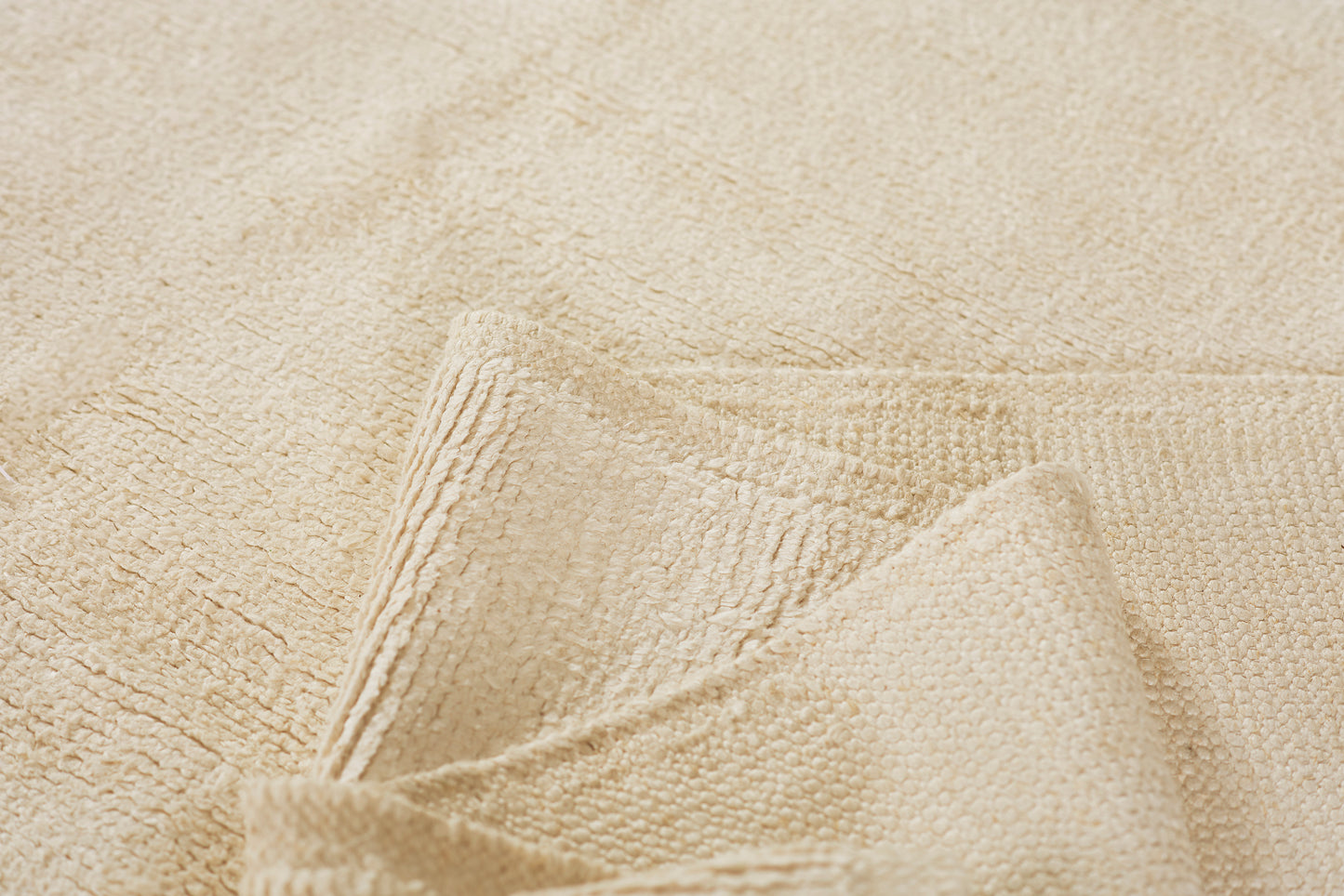 Beige terry towel with folded corner, plush looped cotton texture for bath use.