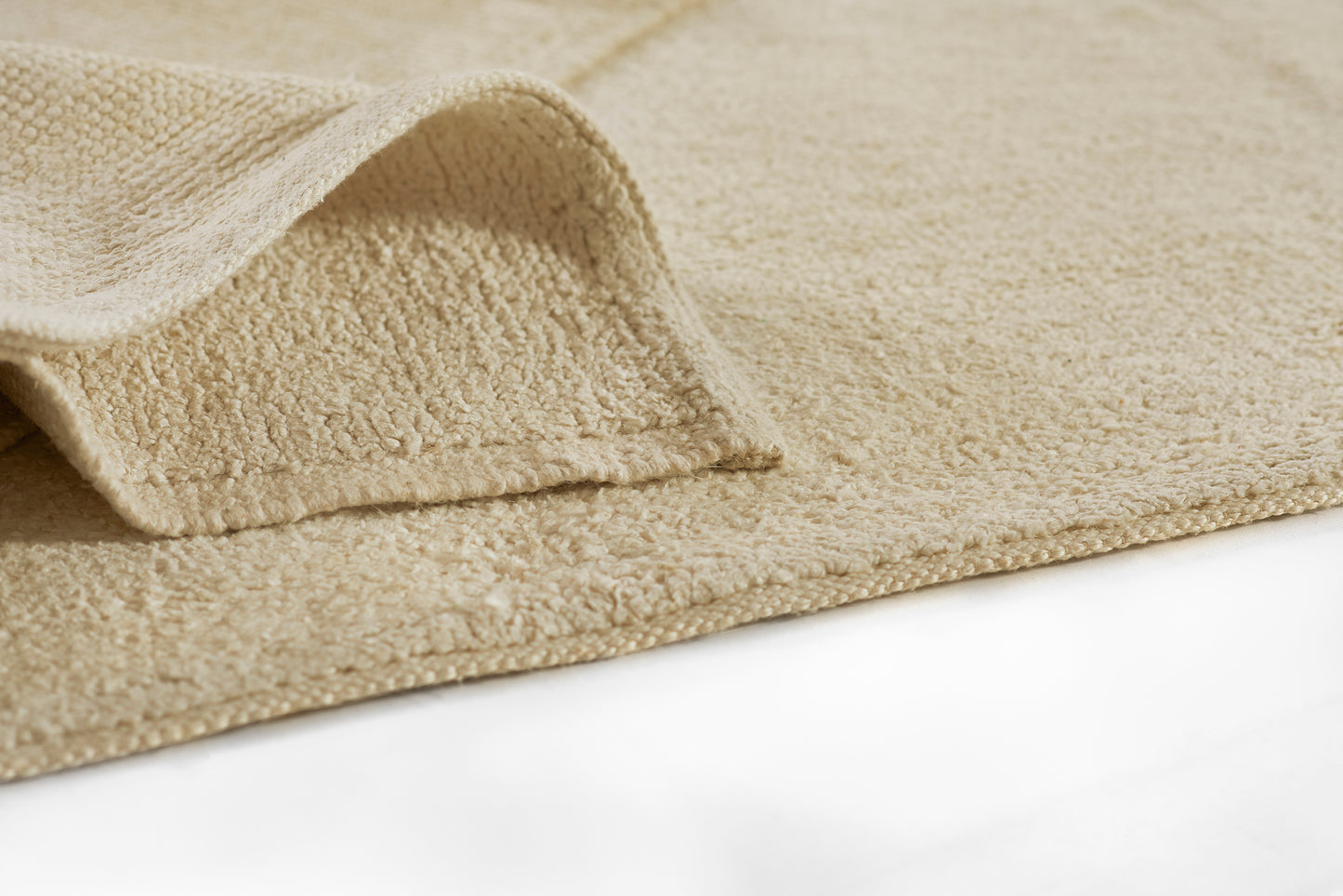 Beige runner rug, close-up of textured weave and folded edge.