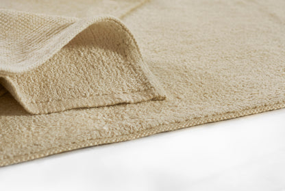 Beige runner rug, close-up of textured weave and folded edge.