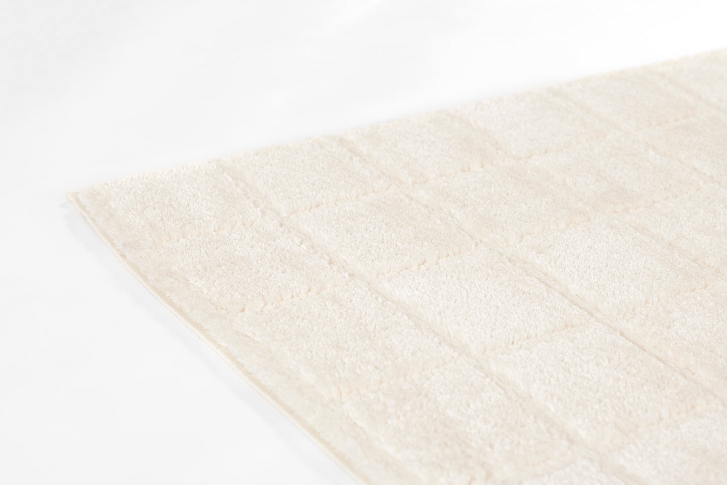 Cream beige plush rug with quilted square panels and soft terry texture.