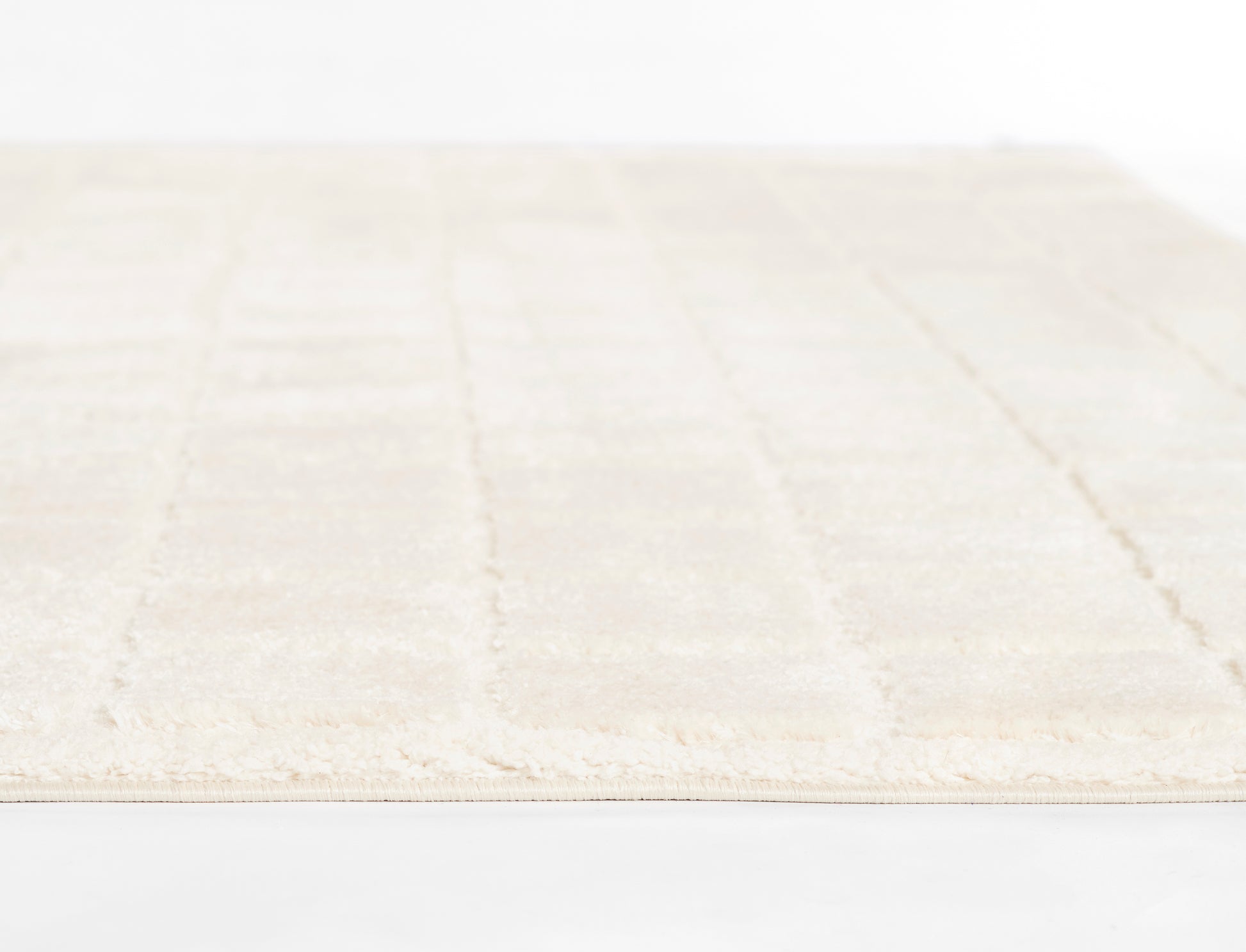Cream ivory rectangular rug with subtle geometric pattern, soft pile and fringe edge