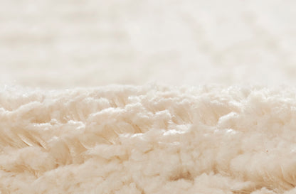 Close-up of cream ivory sherpa fleece fabric with soft, plush texture.
