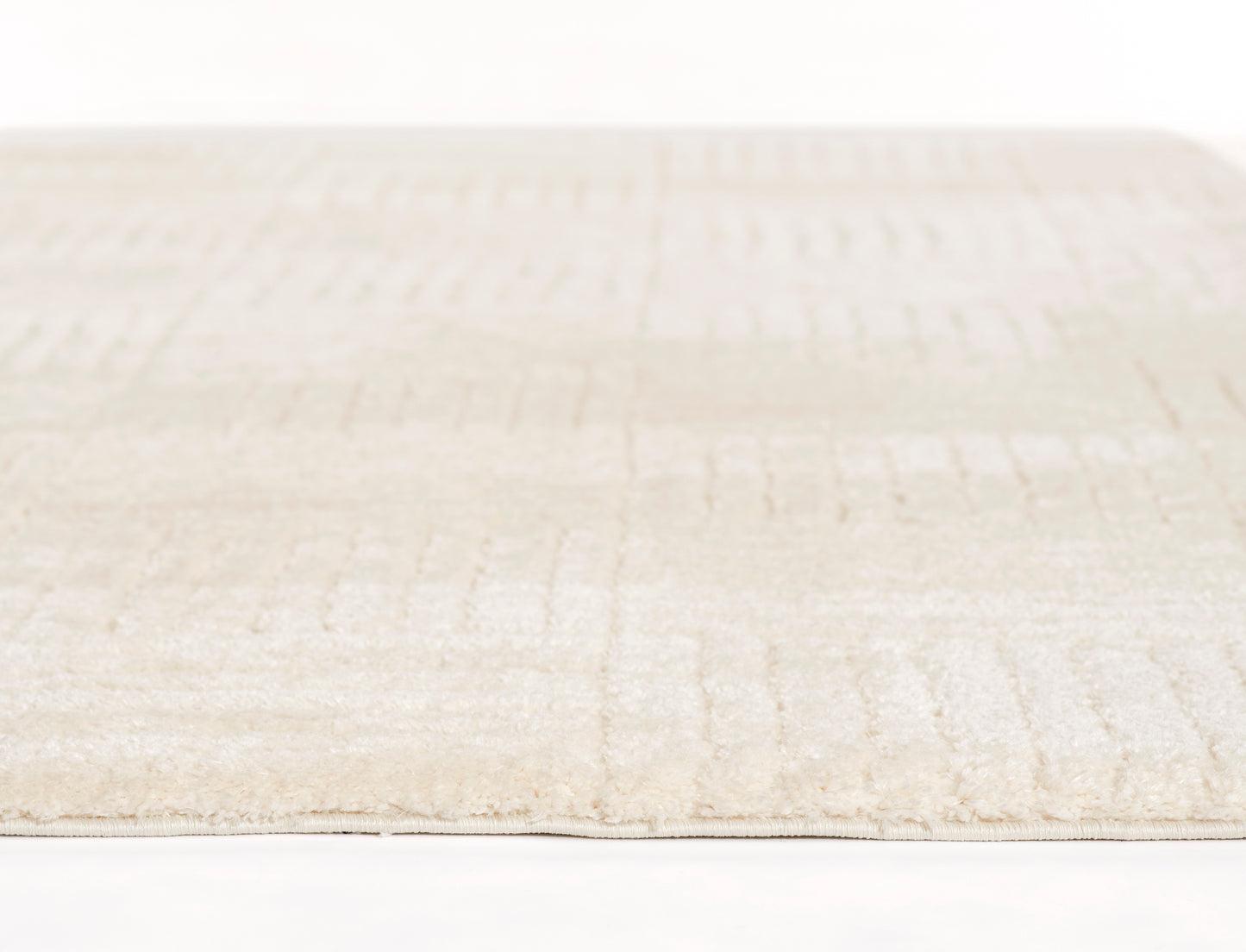 Cream beige rug with soft pile and subtle rectangular pattern; low-profile and cozy.