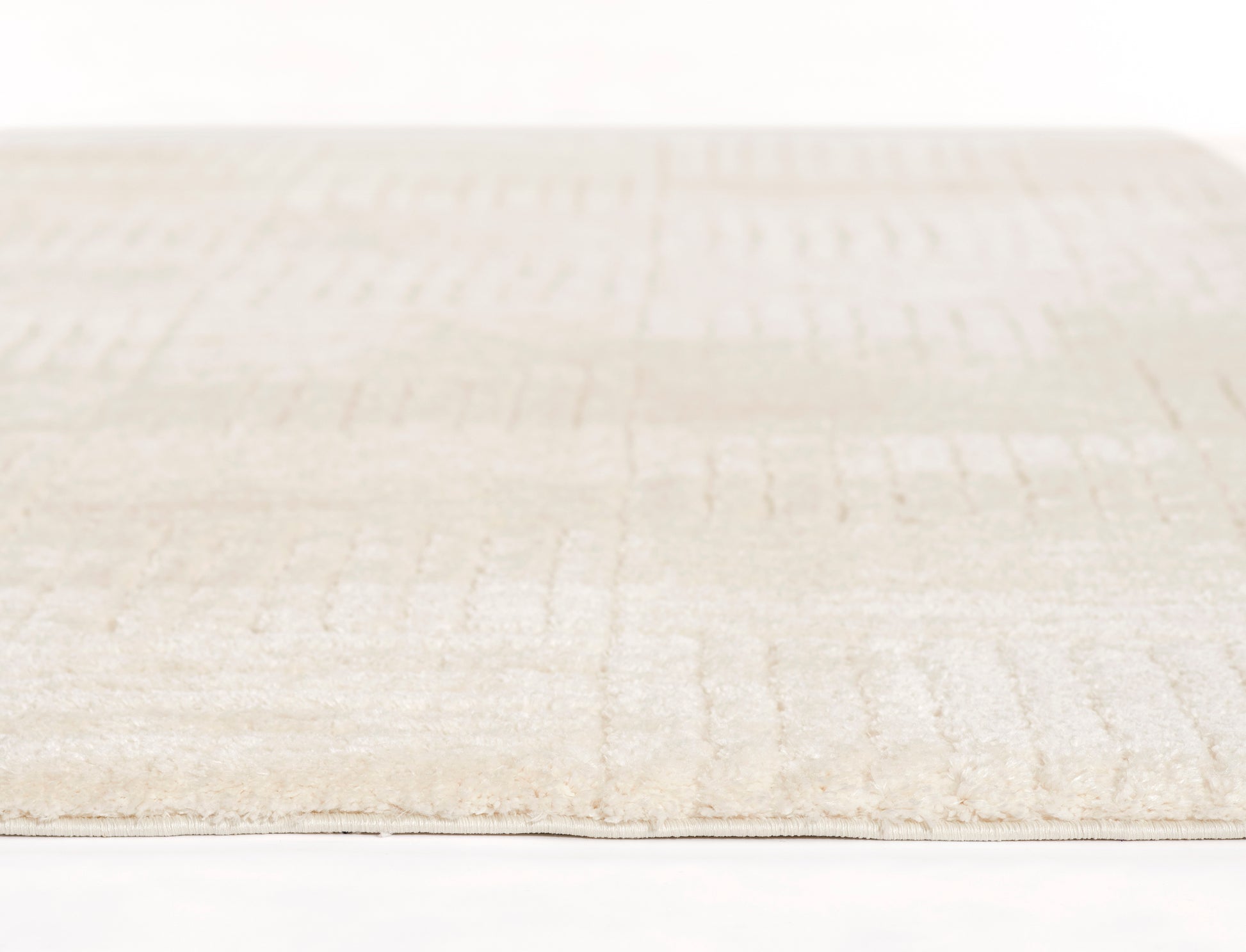 Cream beige rug with soft pile and subtle rectangular pattern; low-profile and cozy.