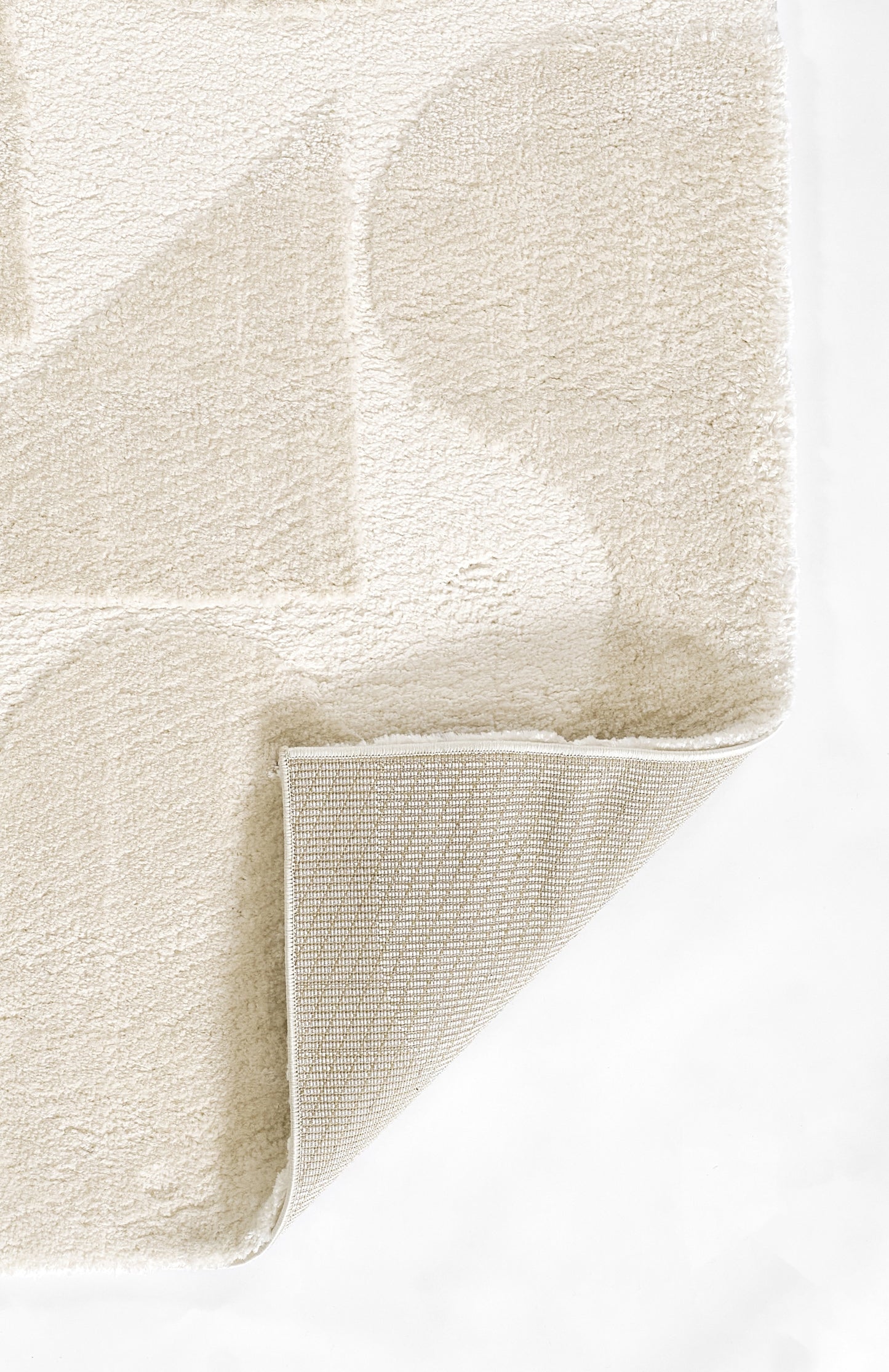 Cream shag rug with plush, textured pile; folded corner reveals woven back.