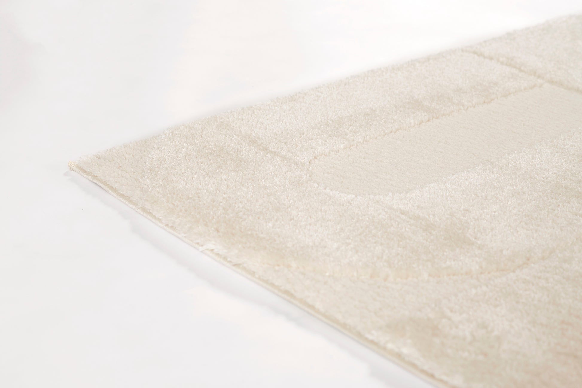 Ivory plush area rug with subtle geometric border, soft textured pile, ideal for living room or bedroom decor.