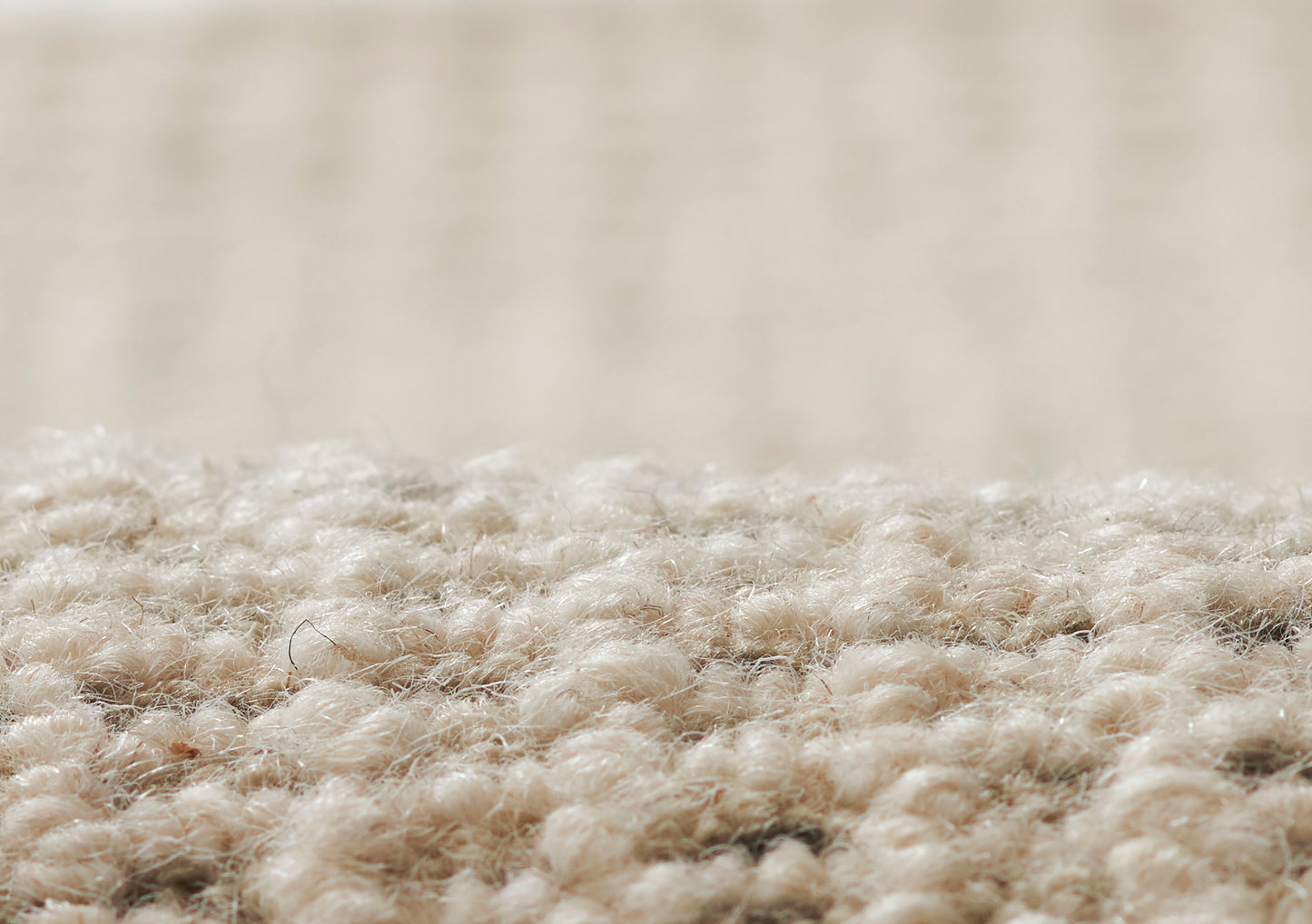 Close-up of beige carpet fibers with a soft textured pile; warm tan rug for living spaces.