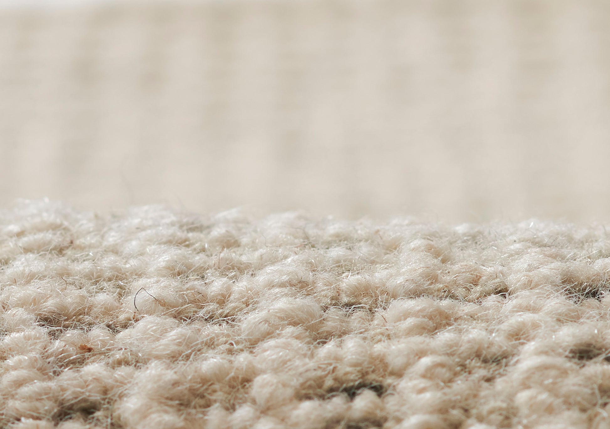 Close-up of beige carpet fibers with a soft textured pile; warm tan rug for living spaces.