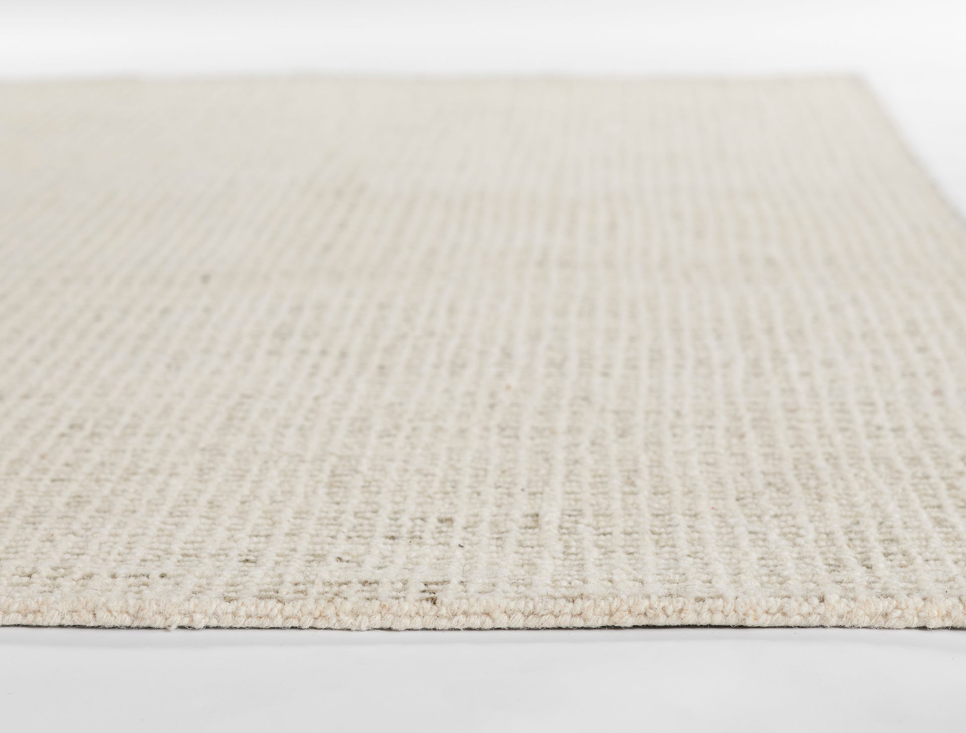 Beige flat-weave rug with natural fiber texture, close-up of woven jute material.
