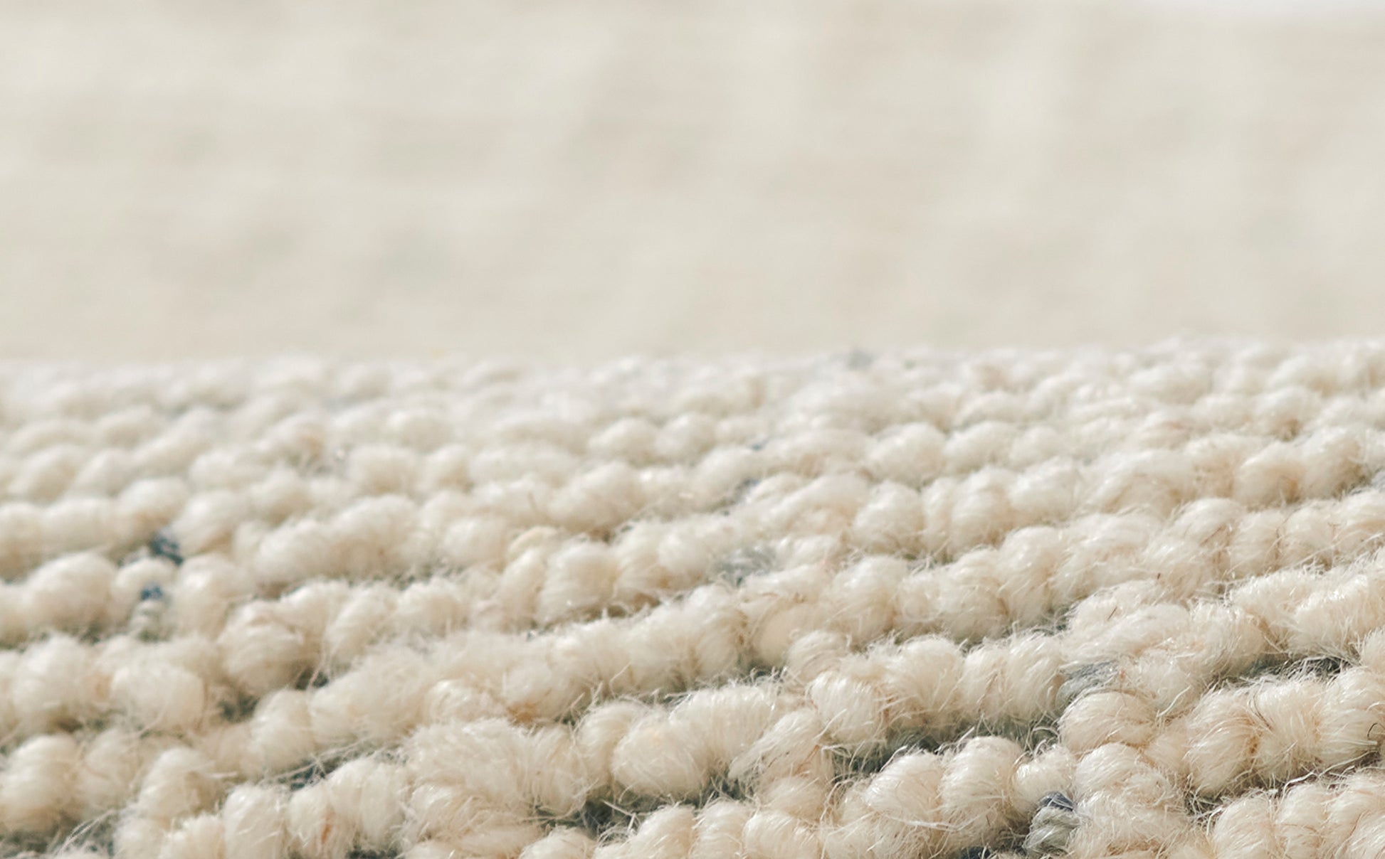 Close-up of cream beige boucle rug fibers with soft, chunky loop pile.
