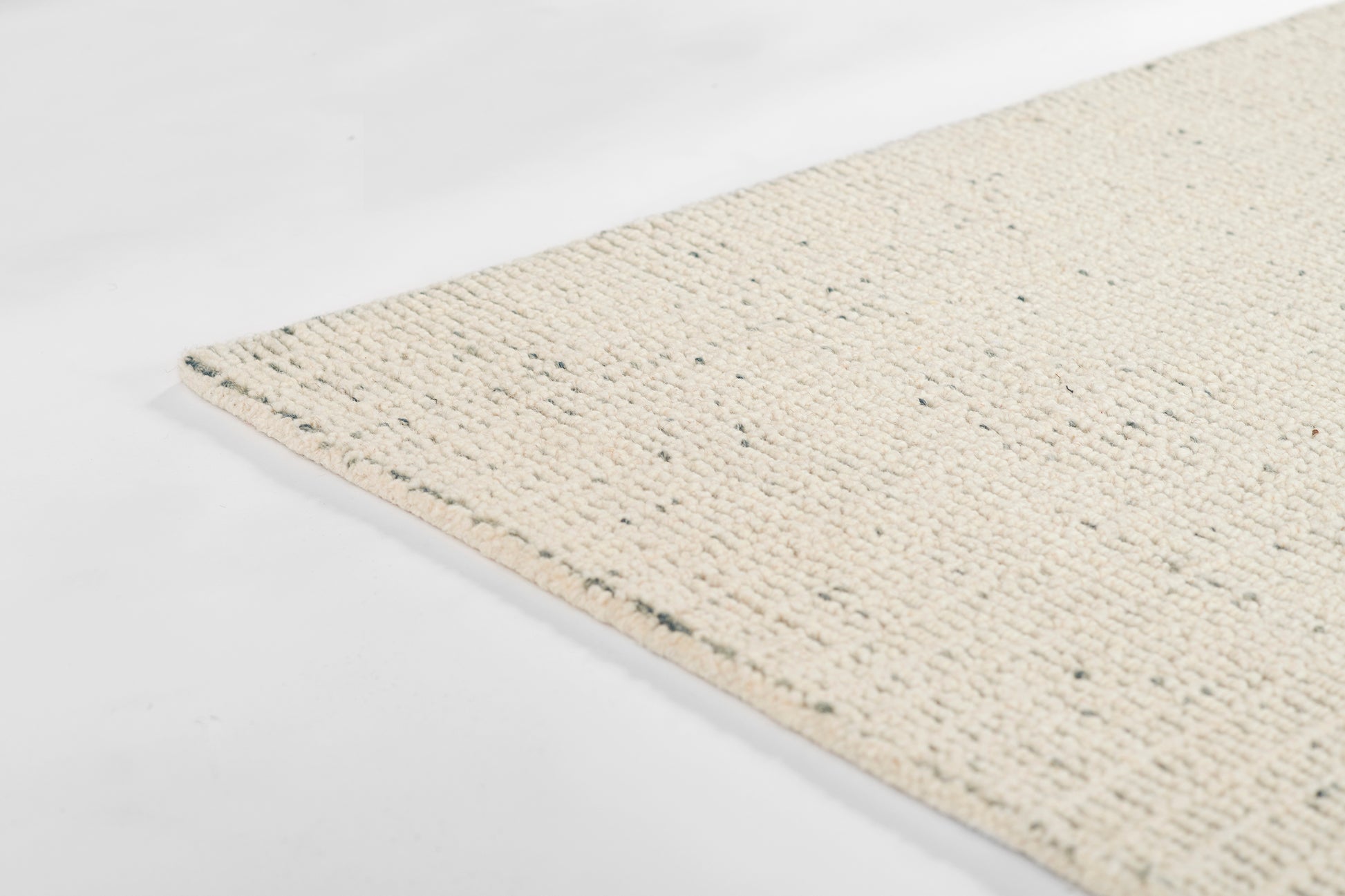 Cream woven jute rug with looped texture and speckled fibers, natural rectangular floor mat.